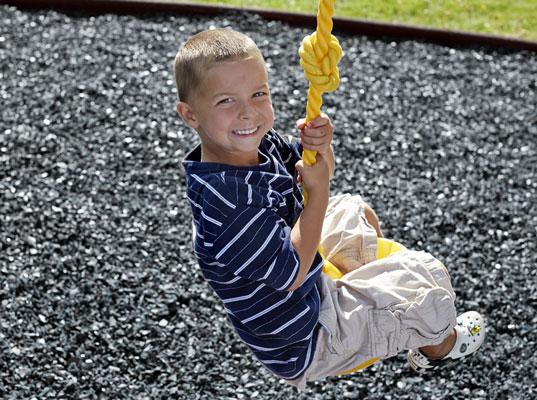 kid playing on black rubber mulch playground