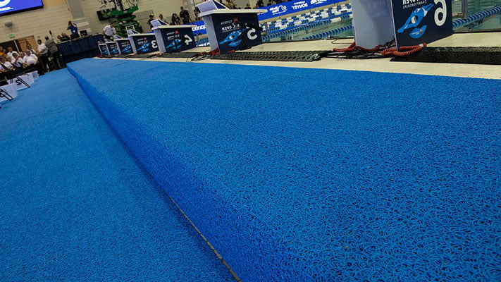 Blue indoor pool rugs around aquatic center pool deck
